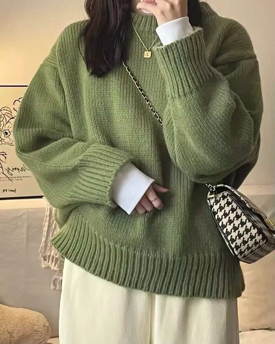 Person wearing an oversized olive green knit sweater and off-white wide-leg trousers.