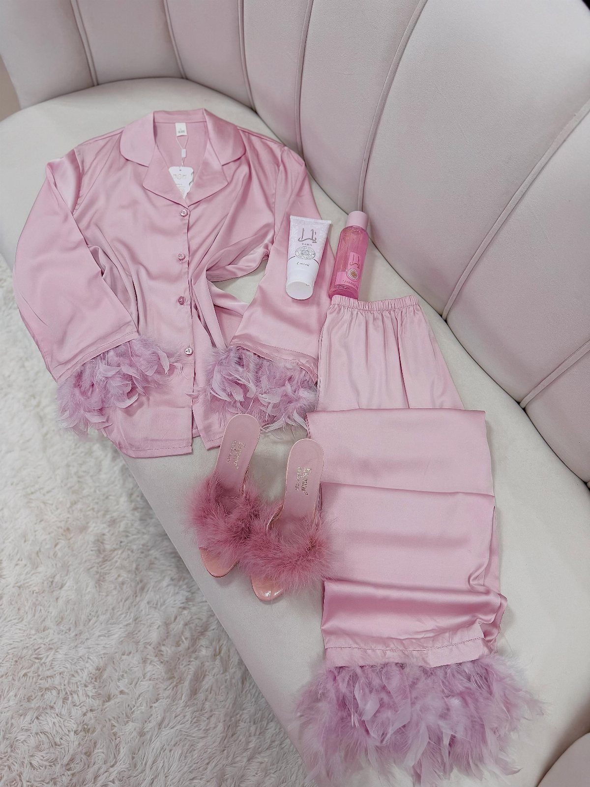 Pink satin pajama set with feather trim and matching feathered high heels on sofa