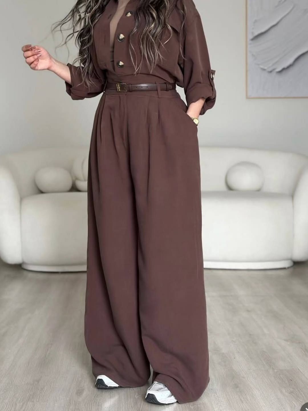 Person wearing a brown wide-leg jumpsuit with a belt and white sneakers.