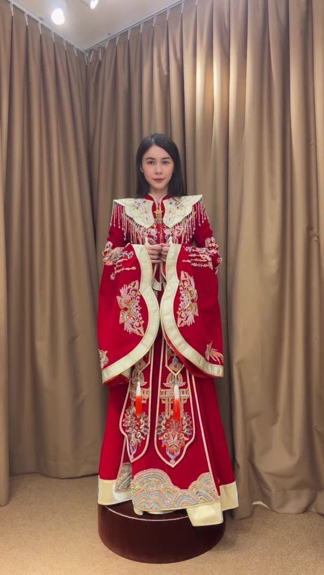 Woman wearing a red and gold embroidered traditional Chinese wedding dress and capelet.