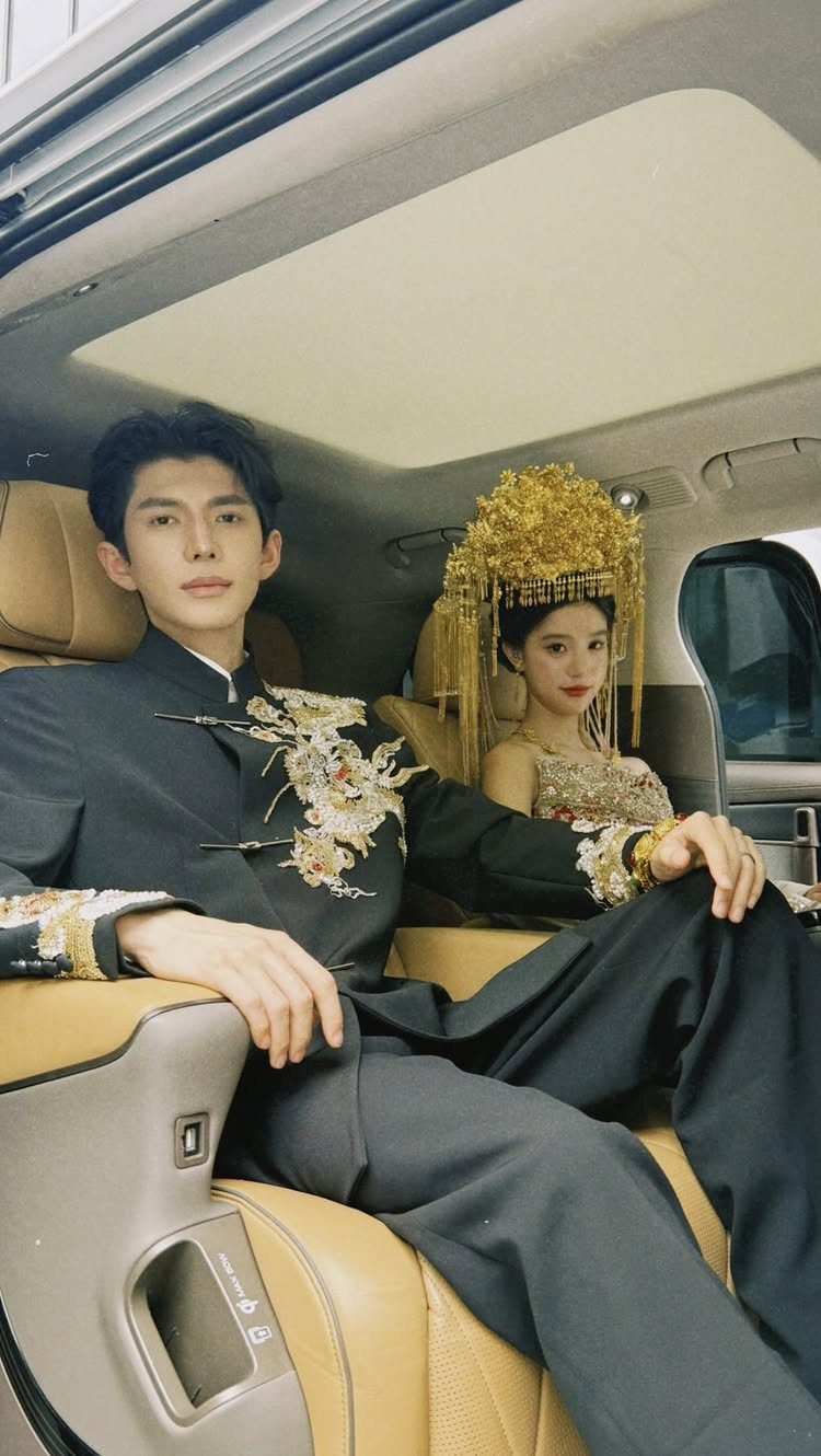 Couple in traditional black and gold Chinese wedding attire sitting in a car