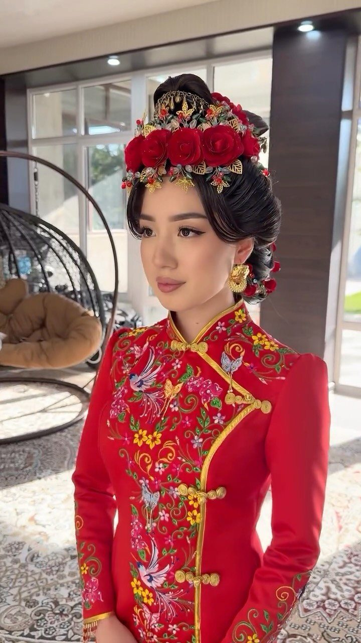 Woman in a red embroidered Qipao with a red floral headpiece posing indoors.