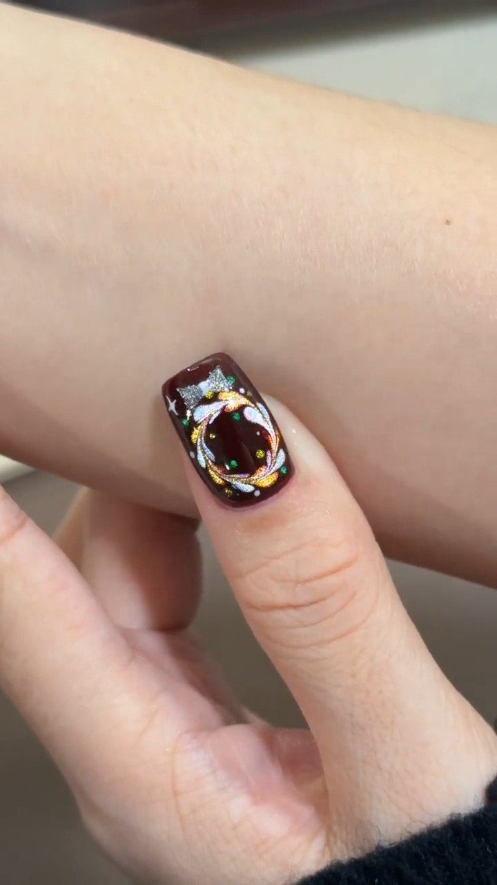 Short burgundy nail featuring a detailed white and gold Christmas wreath design.