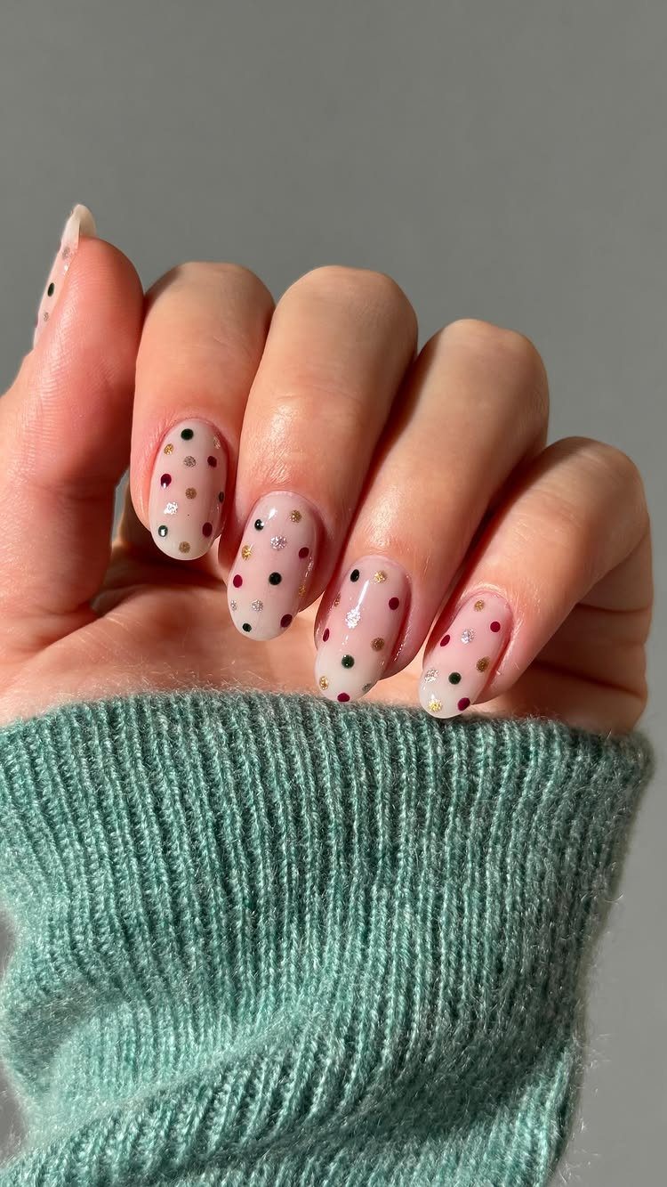 Short nails with milky white polish and red, gold, and black glitter polka dots.
