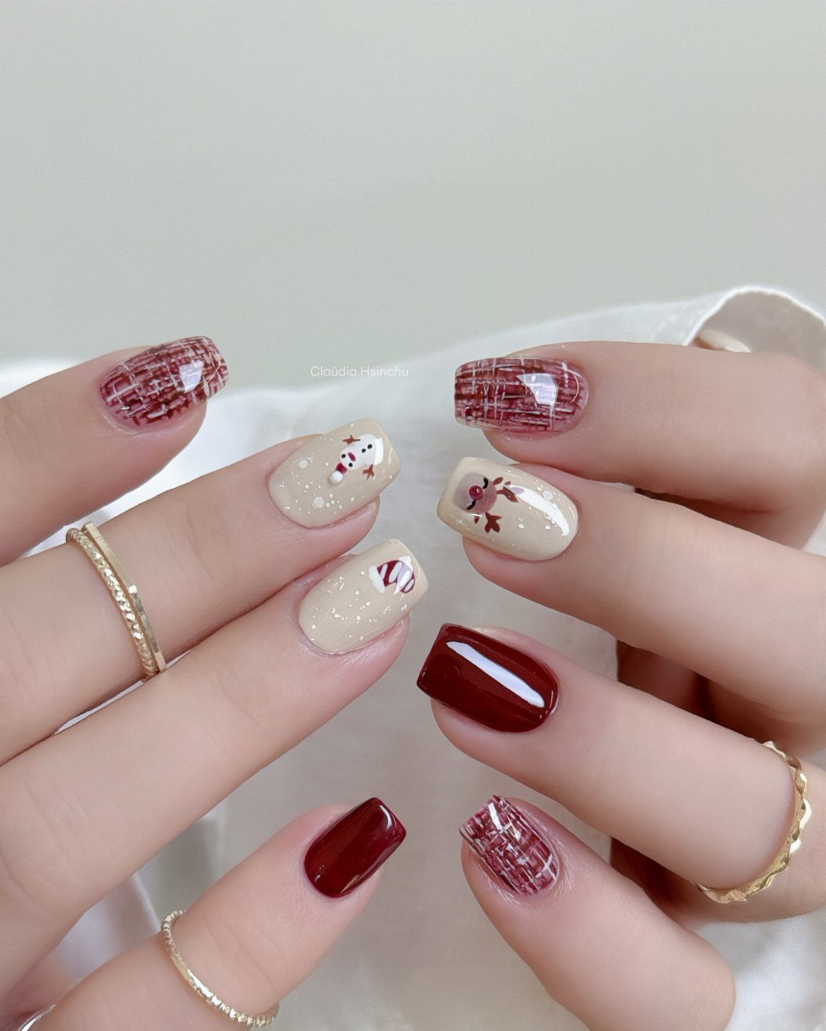Short nails with red plaid, deep red, and cream Christmas nail art designs.