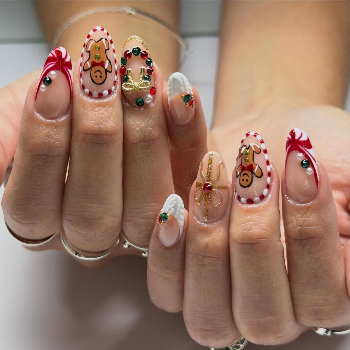 Short nails with festive Christmas art featuring reindeer, red swirls, and gold beads.