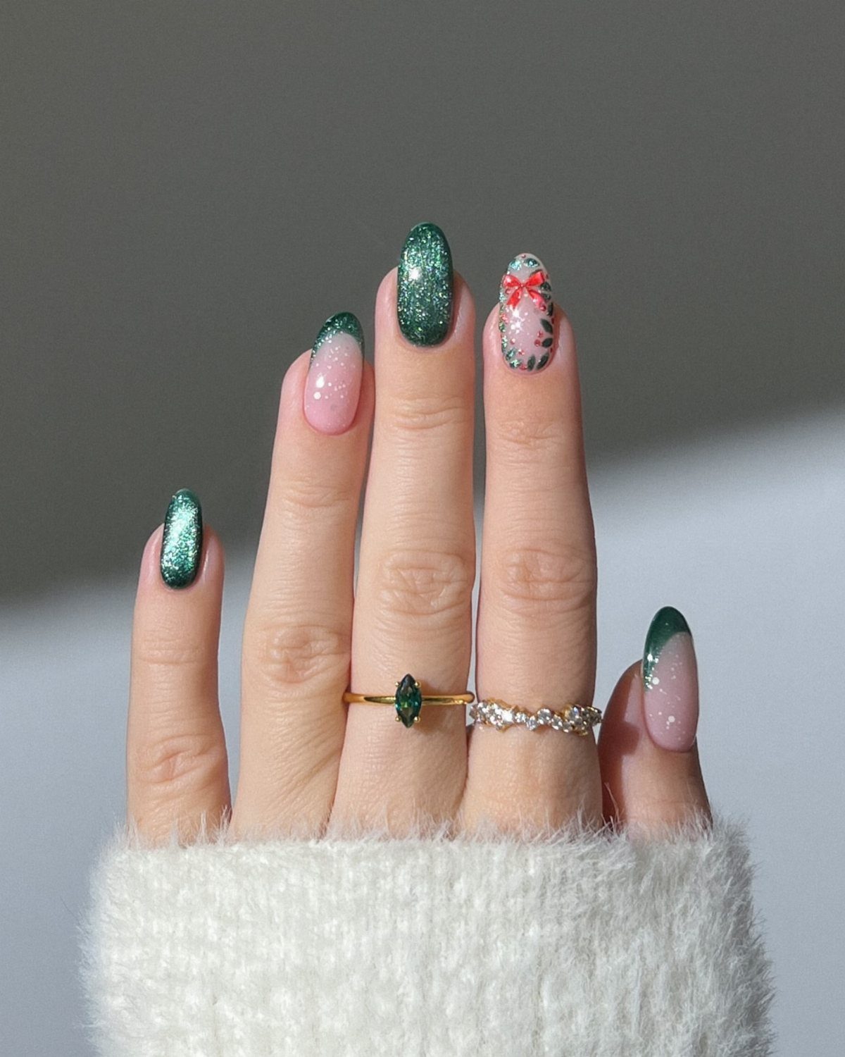 Short nails with green glitter and festive holiday art on a hand.