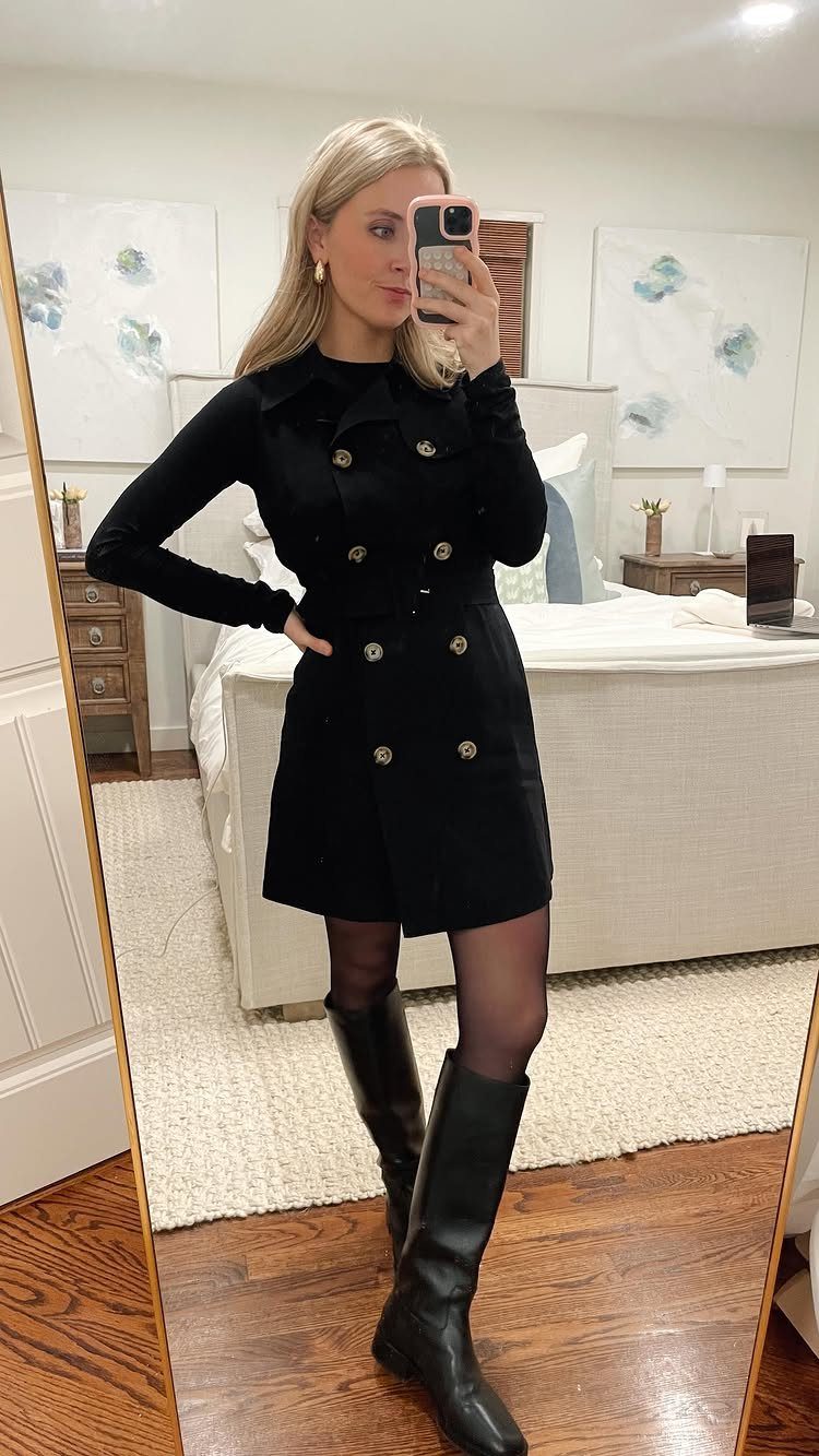 Woman in black double-breasted dress, sheer black tights, and knee-high black leather boots.