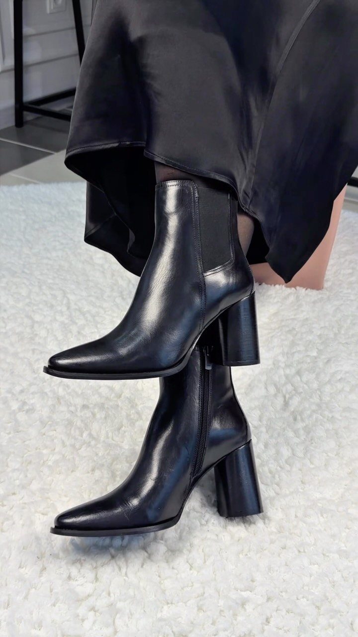Black leather ankle boots with block heels paired with a black satin dress.