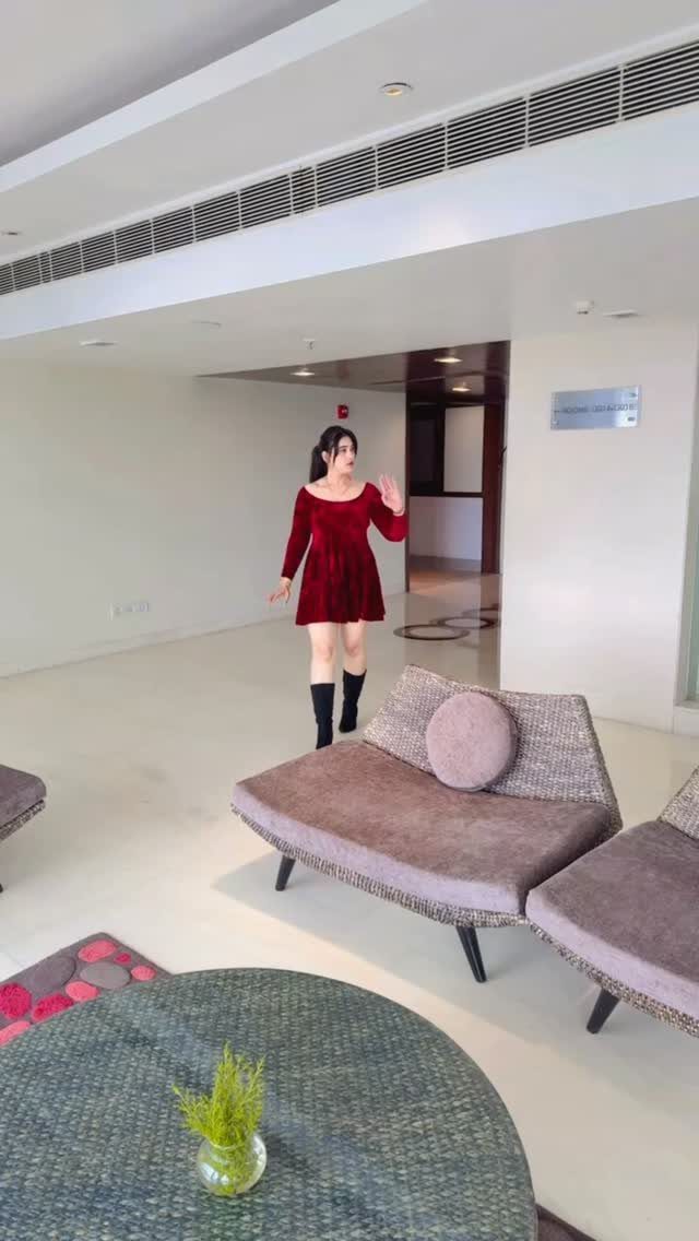 Woman wearing a short red dress and black knee-high boots in a modern room