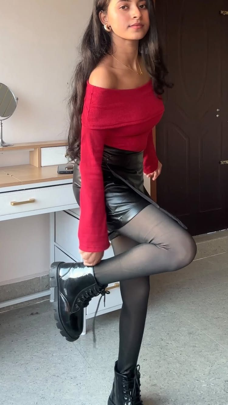 Woman in red top and black leather skirt wearing chunky black lace-up boots.