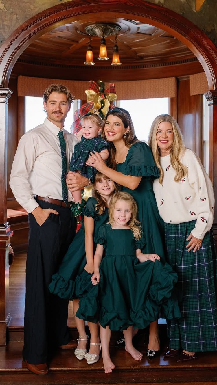Family posing in coordinated green and white holiday outfits in a wooden interior.