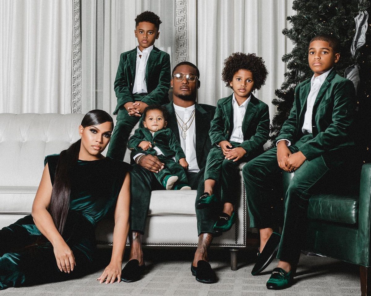 Family wearing matching dark green velvet holiday outfits posing in a living room.