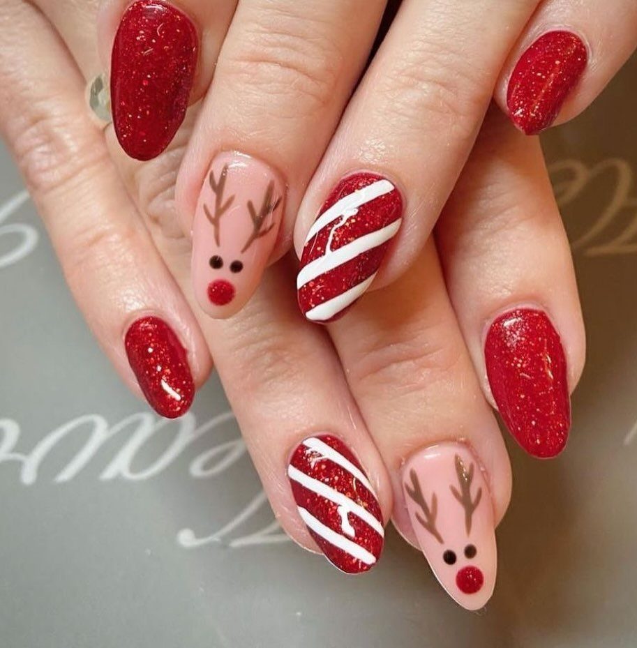 Red and nude almond nails with candy cane stripes and reindeer designs.