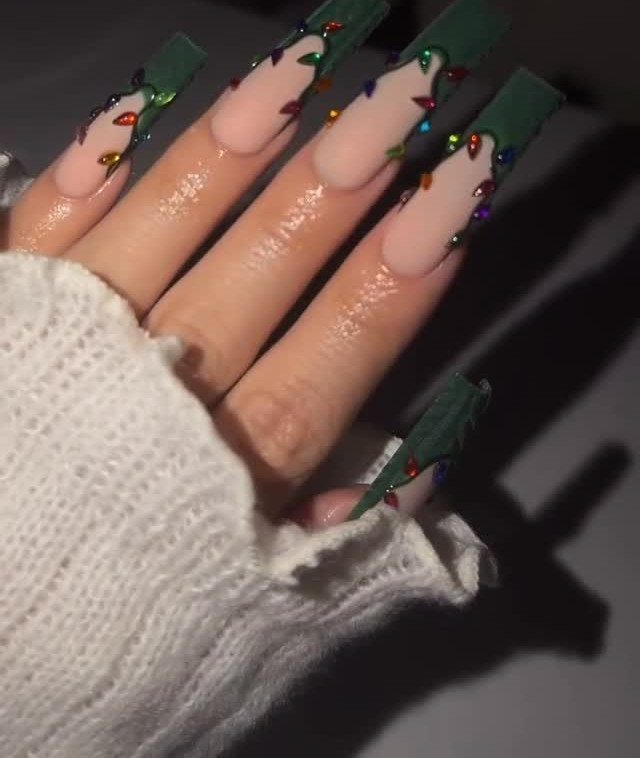 Long coffin nails with nude bases, green tips, and colorful 3D Christmas lights.