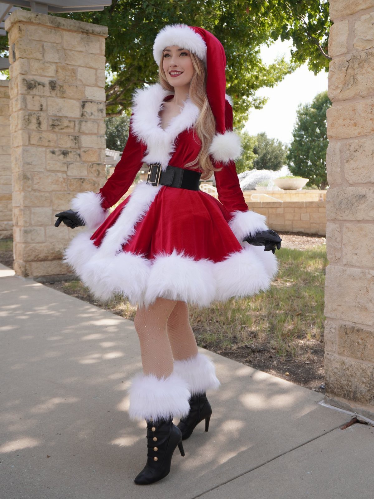 Woman in a red velvet Santa-inspired dress with white fur trim and hat.