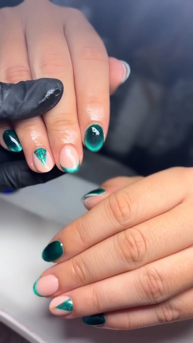 Manicured nails with dark green polish and minimalist glittery green tree accent designs.