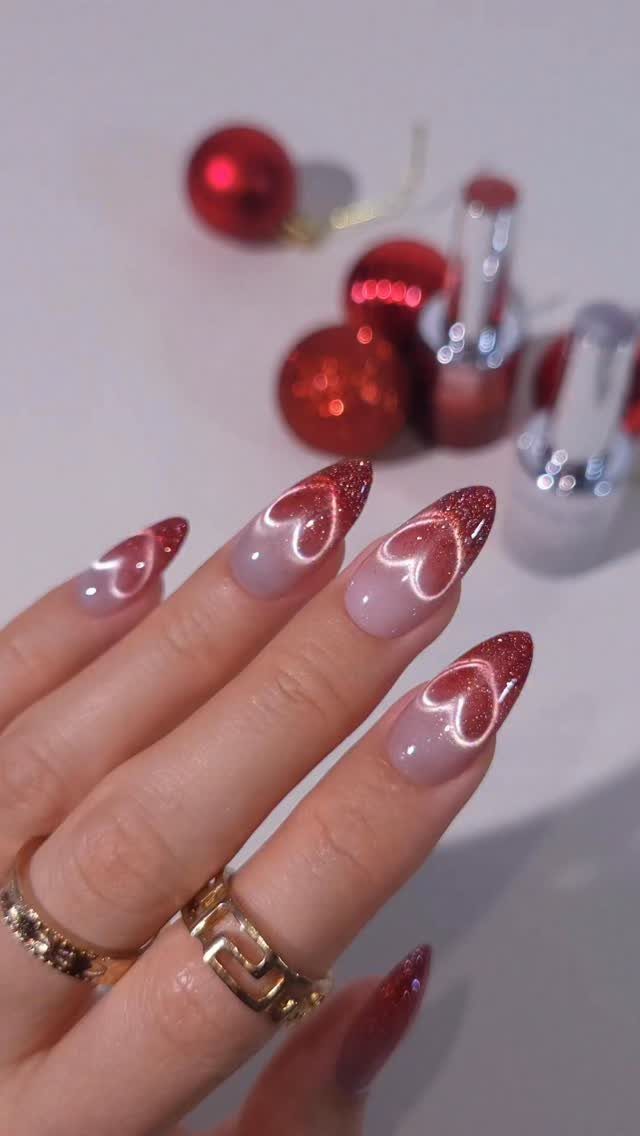 Almond nails with red and white ombré gradient, heart art, and glitter tips.
