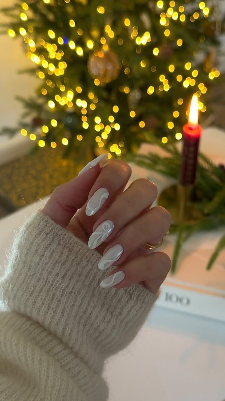 White almond-shaped nails with 3D swirls against a blurred Christmas tree background