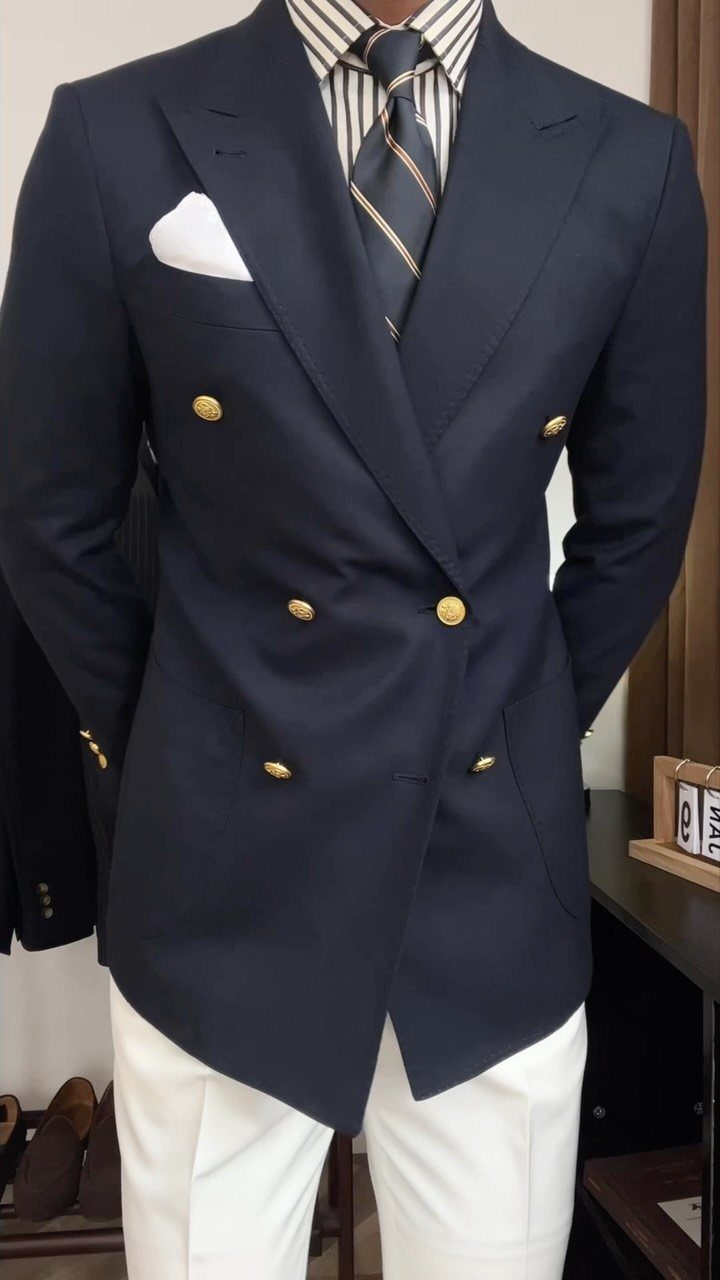 Man wearing a navy double-breasted blazer with gold buttons and white trousers.