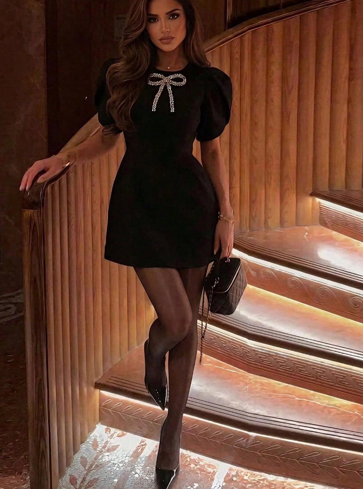 Woman in a short black dress with a sparkly bow on wooden stairs
