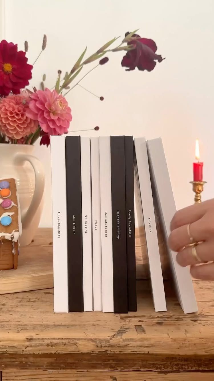 Row of white and black hardcover photo books on a rustic wooden table.
