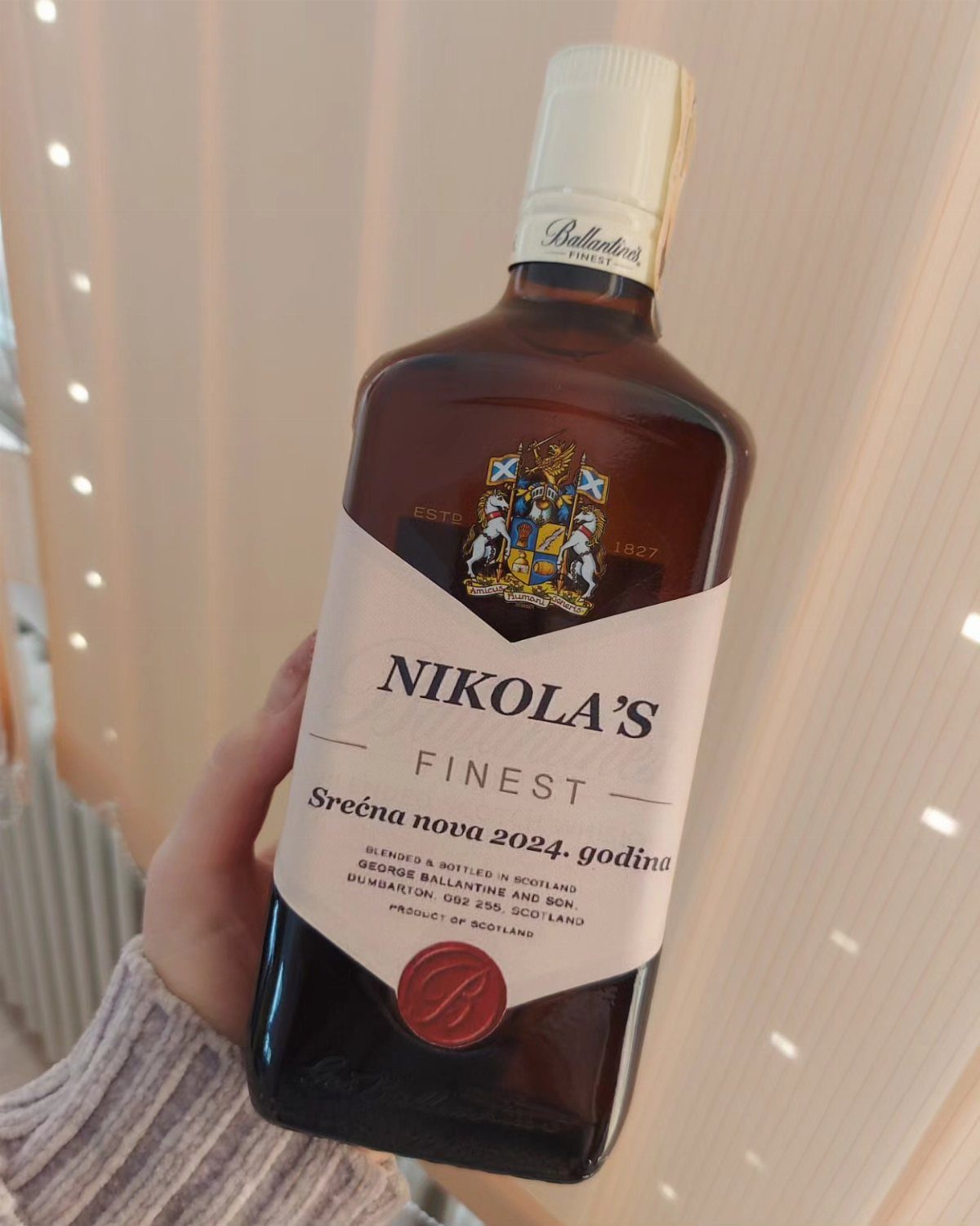 Personalized bottle of scotch whisky with a custom label held by a hand