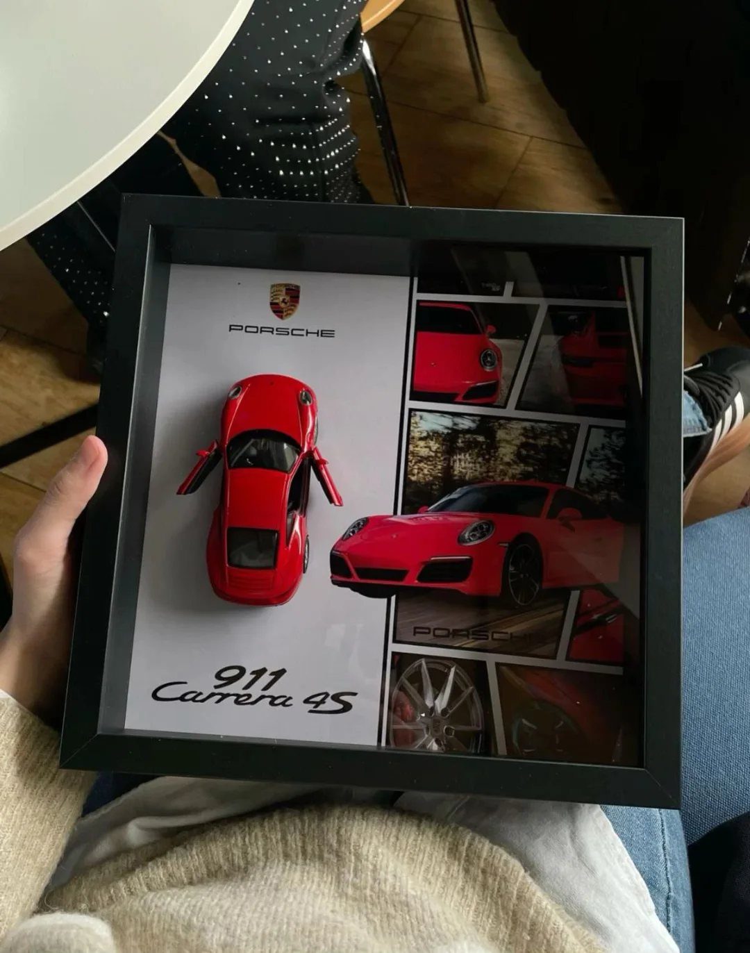 Red Porsche model car and photos in a black shadow box frame.