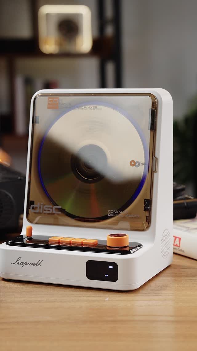 White modern CD player with a spinning disc on a wooden table