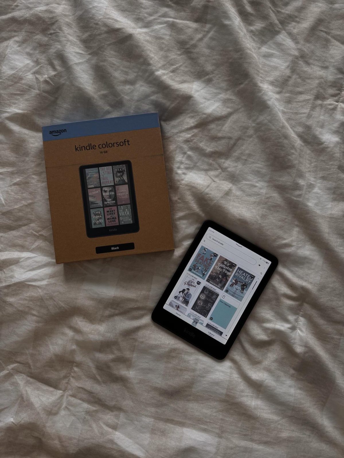 Kindle Colorsoft e-reader and its original packaging on a white textured cloth.