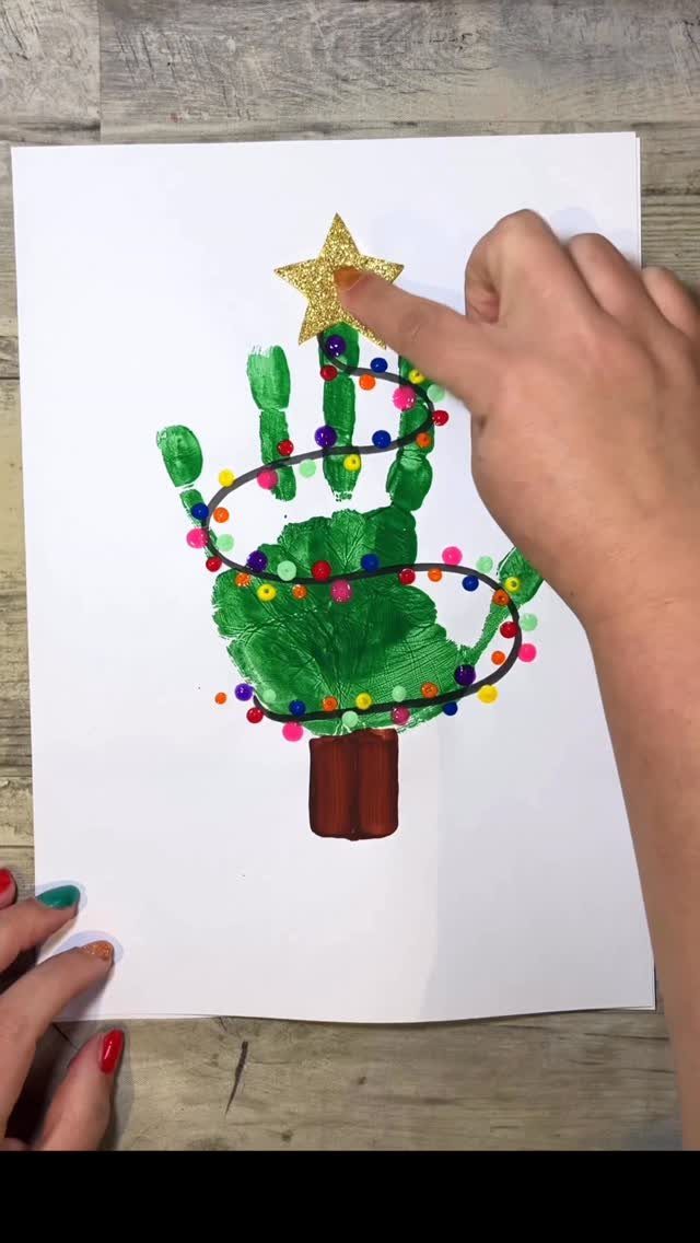 Green handprint painting shaped like a Christmas tree with a gold glitter star.