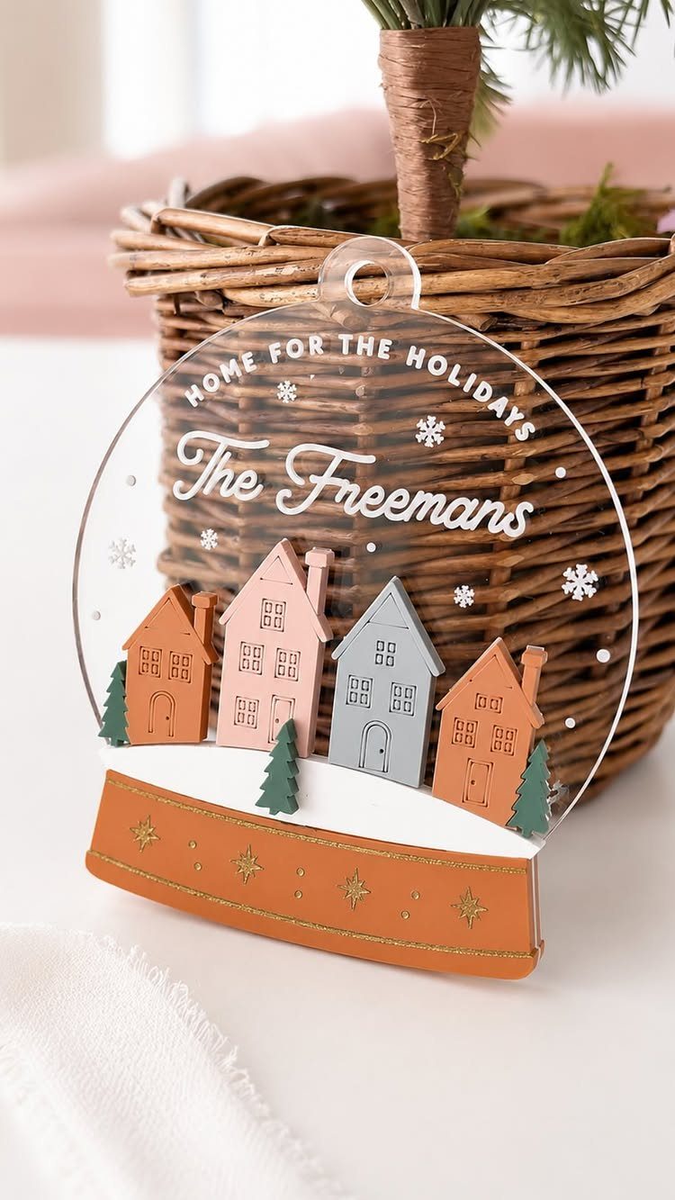Circular acrylic Christmas ornament with colorful houses and personalized family name text.