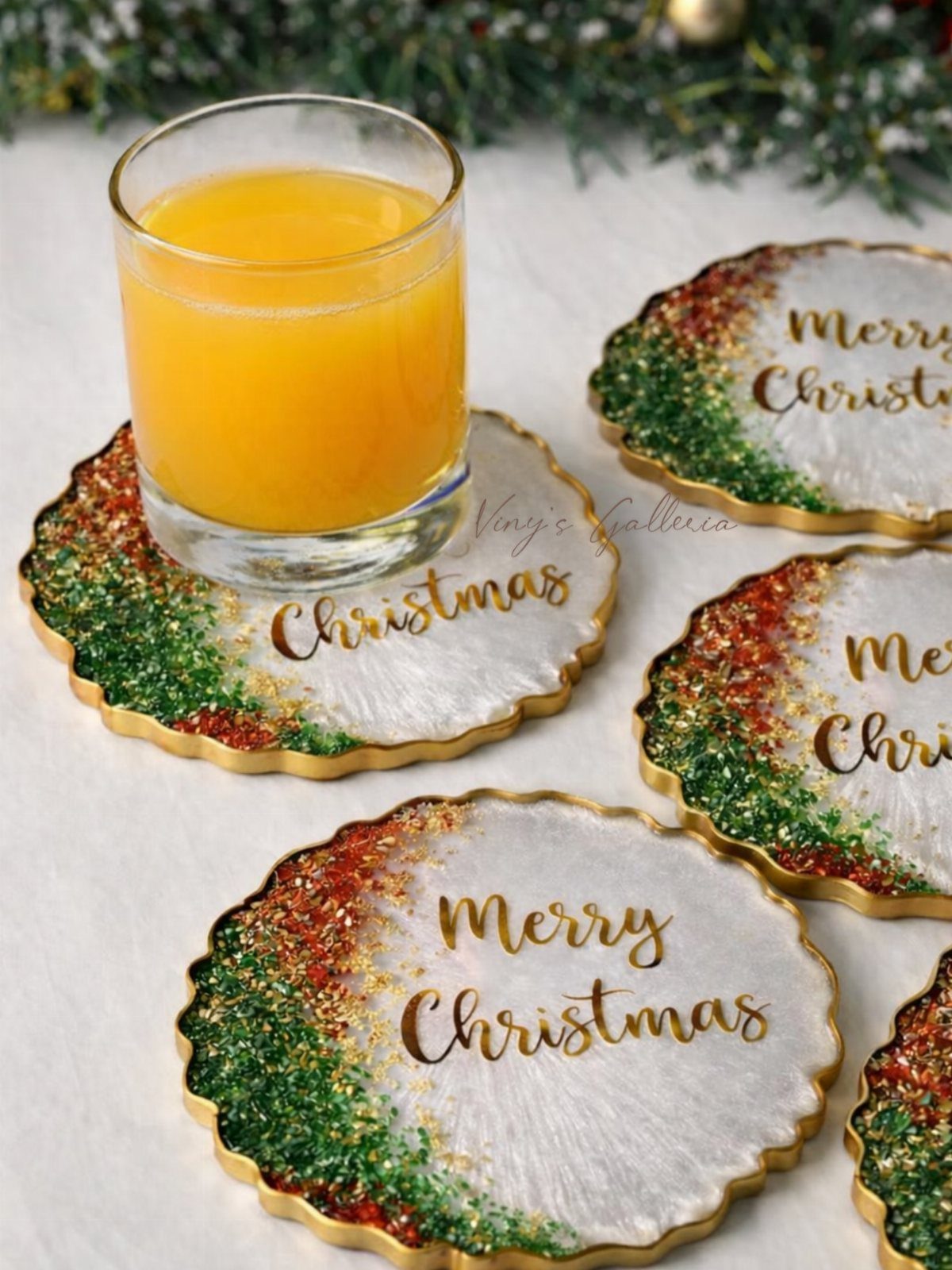 Resin Christmas coasters with gold rims and glitter, one holding orange juice.