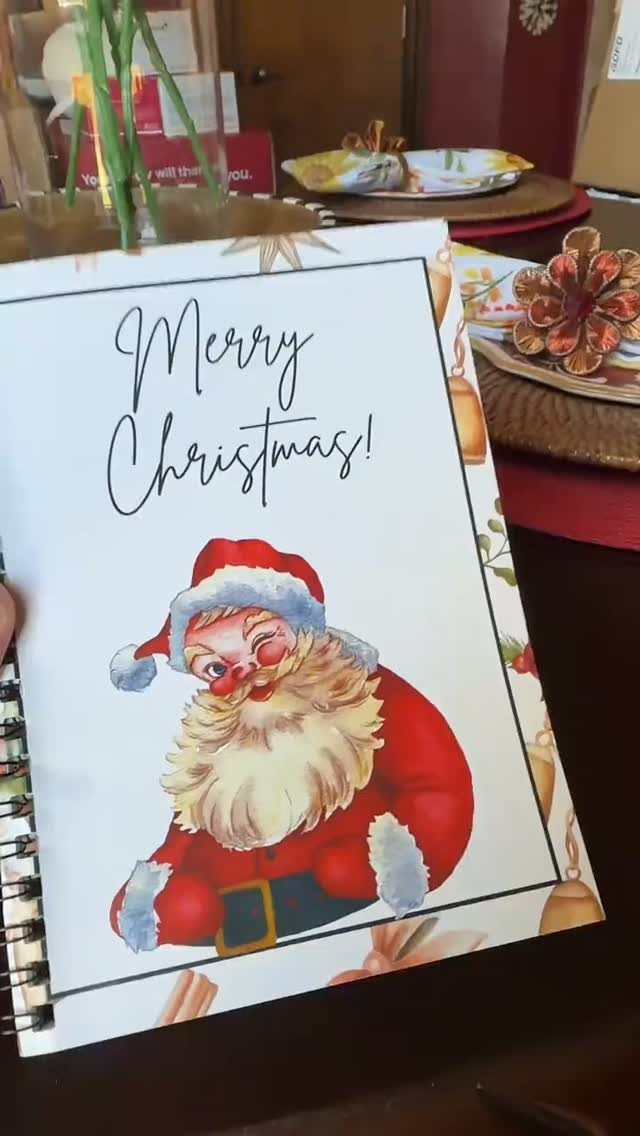 Spiral notebook with Santa Claus illustration and Merry Christmas text on a table