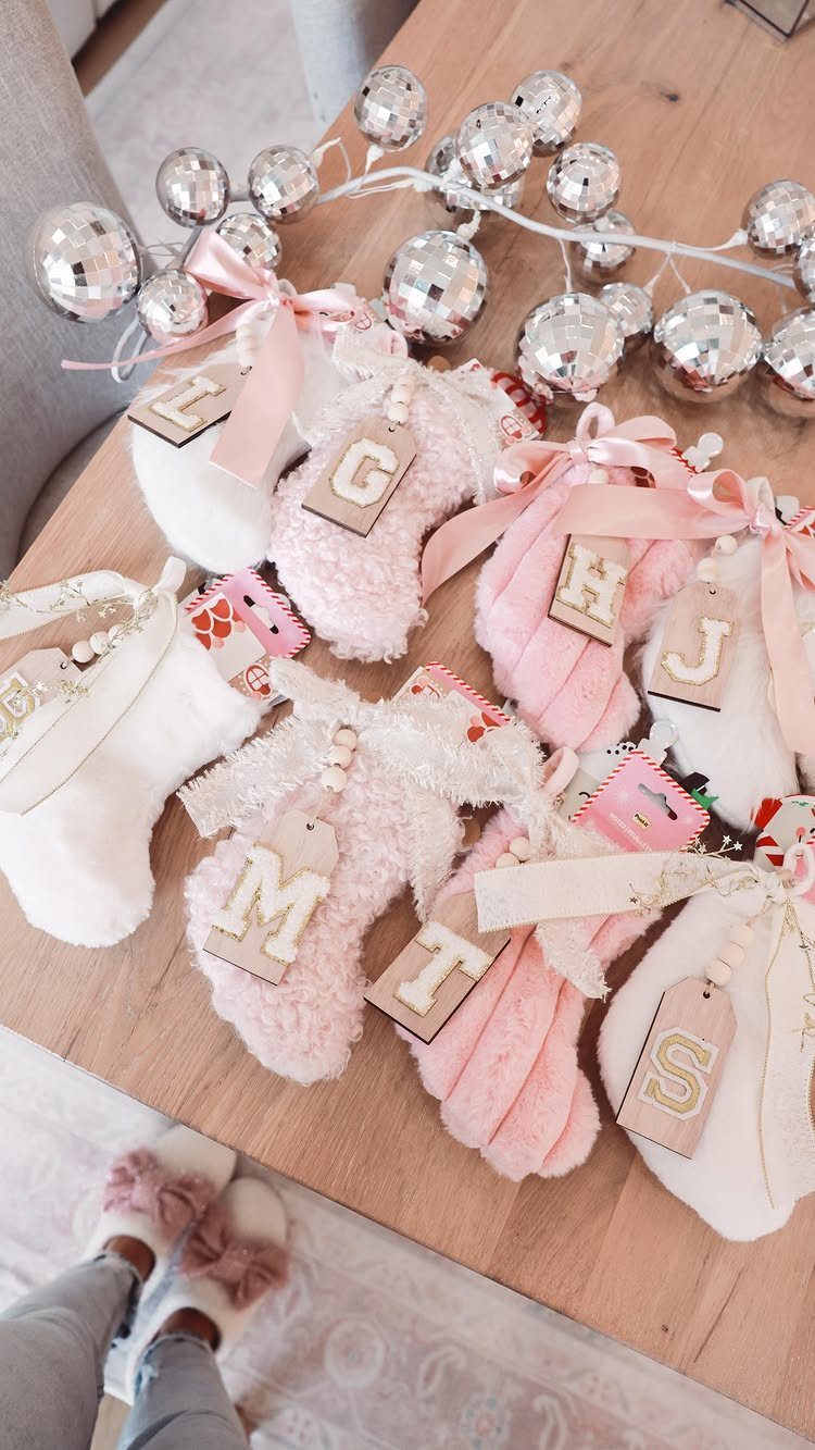 Fluffy pink and white socks with wooden letter tags on a wooden table.
