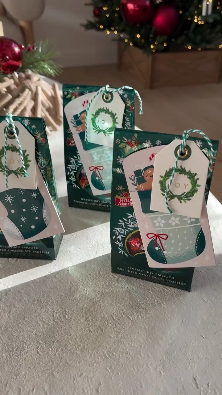 Three green chocolate truffle gift boxes with festive tags on a grey surface.