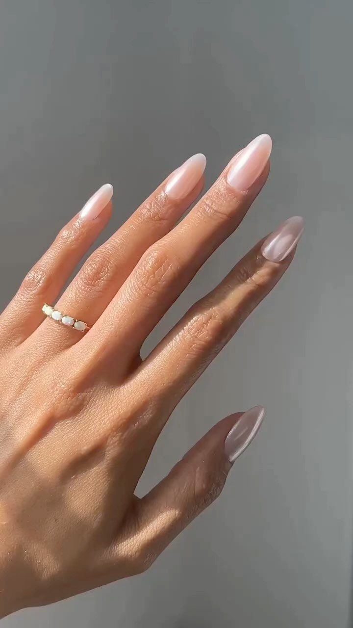 Hand with pearlescent white glazed donut nails and a gold ring.