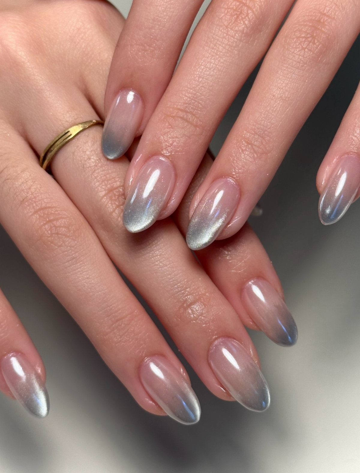 Almond-shaped nails with a silver chrome ombre gradient effect on a hand.
