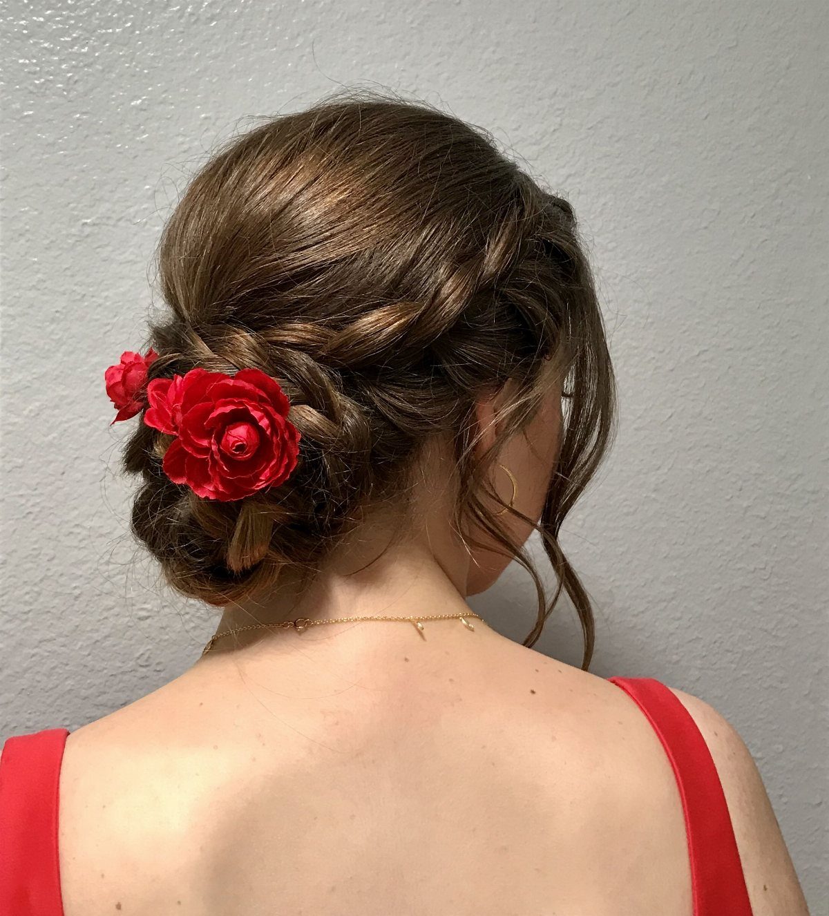 Brown hair updo with a low bun and red fabric roses.