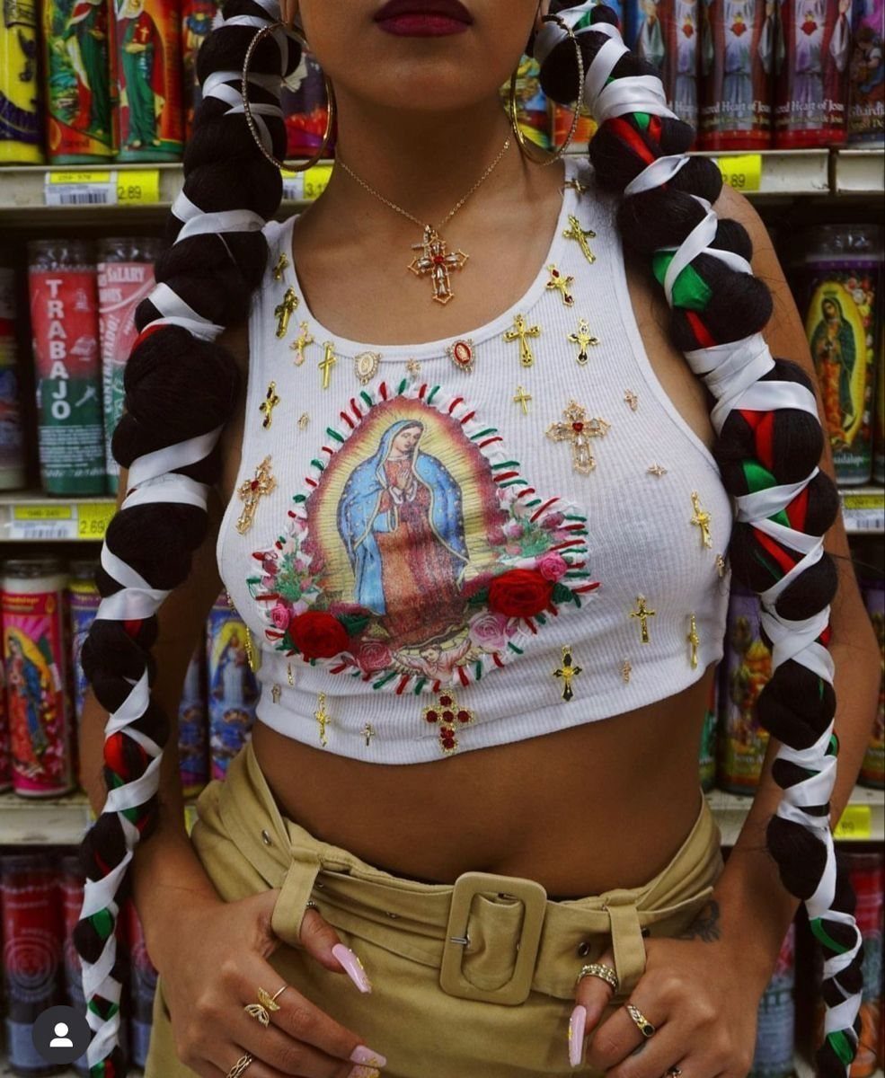 Person with thick braids wrapped in white, red, and green ribbons wearing hoop earrings.