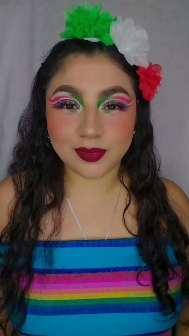 Woman wearing colorful sarape top and matching green, white, and red makeup.