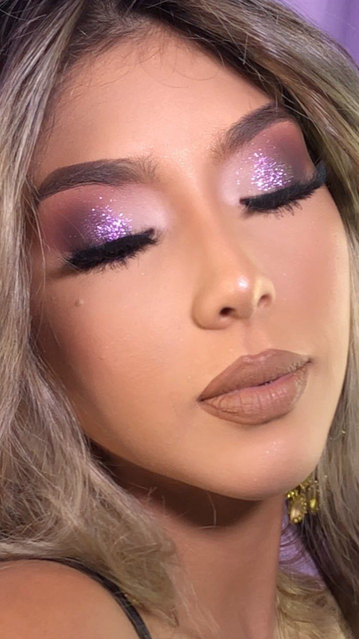 Woman with closed eyes wearing purple and pink shimmery eyeshadow and nude lipstick