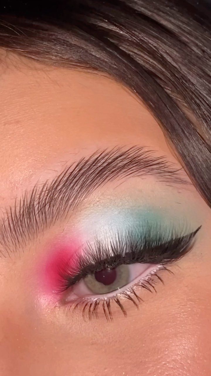 Eye with pink, white, and green eyeshadow and sharp black winged eyeliner.