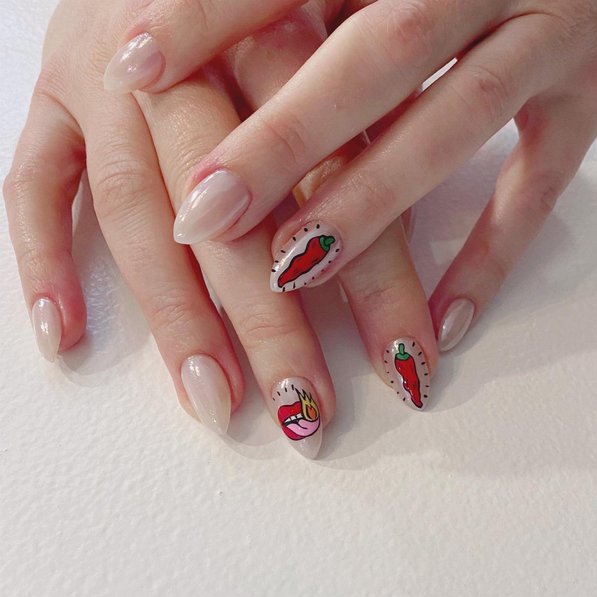 Almond-shaped nails featuring hand-painted red chili peppers and a flaming lip design.