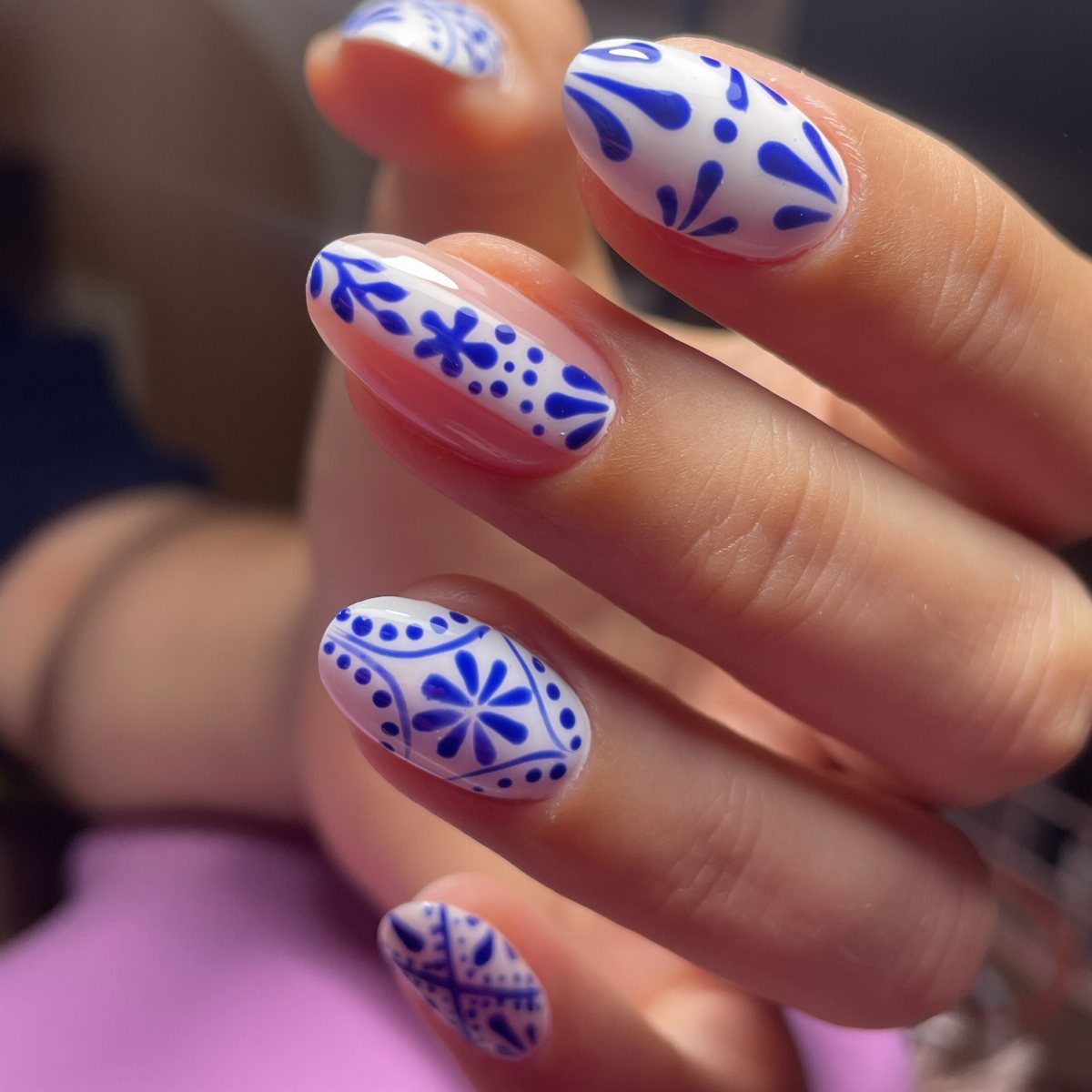 Almond-shaped nails with white and blue Talavera tile inspired floral patterns.