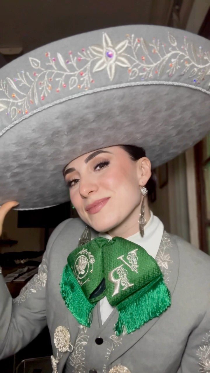 Woman wearing a grey embroidered charro suit and matching sombrero with green bow tie.