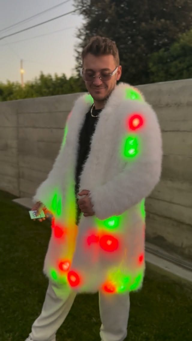 Man wearing a white faux-fur coat with glowing red and green LED lights.