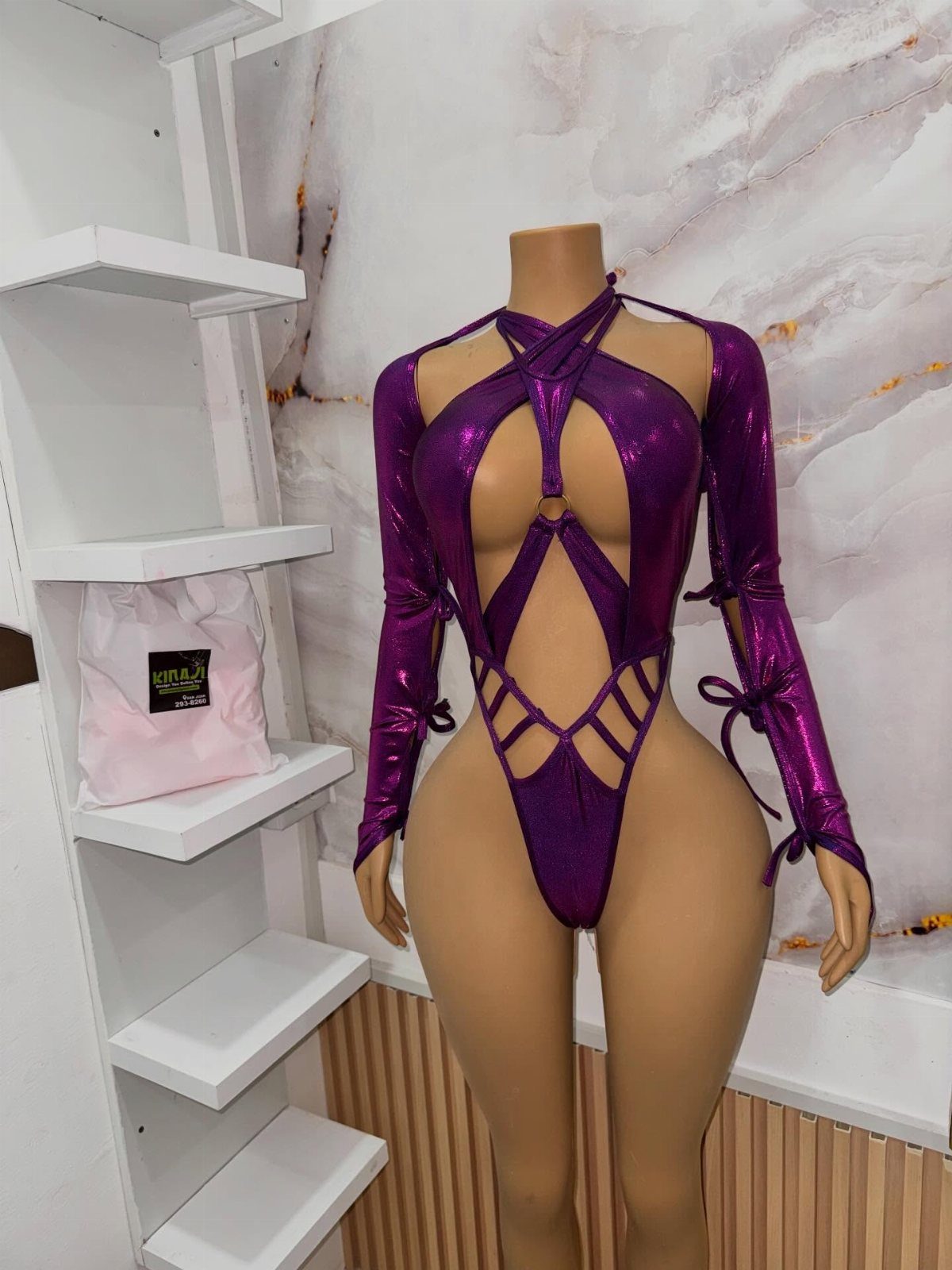 Metallic purple sequin bodysuit with cut-outs displayed on a tan female mannequin.