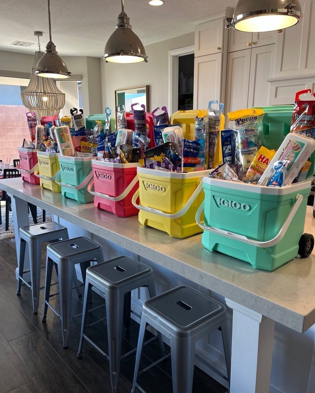 Colorful plastic buckets filled with snacks and toys on a white kitchen counter.