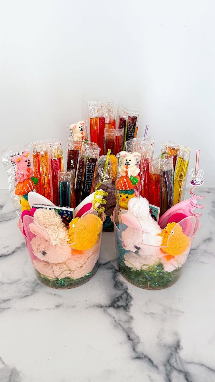 Two Easter baskets with plush bunnies and bags of colorful candy on marble.